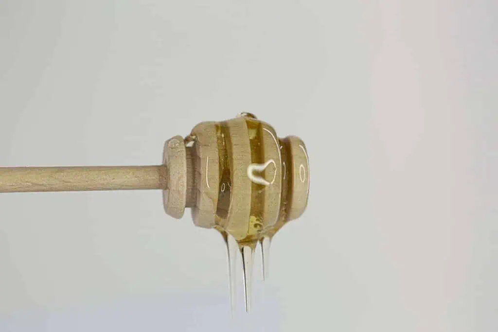 Honey dripping from a honey dipper showcasing natural honey.