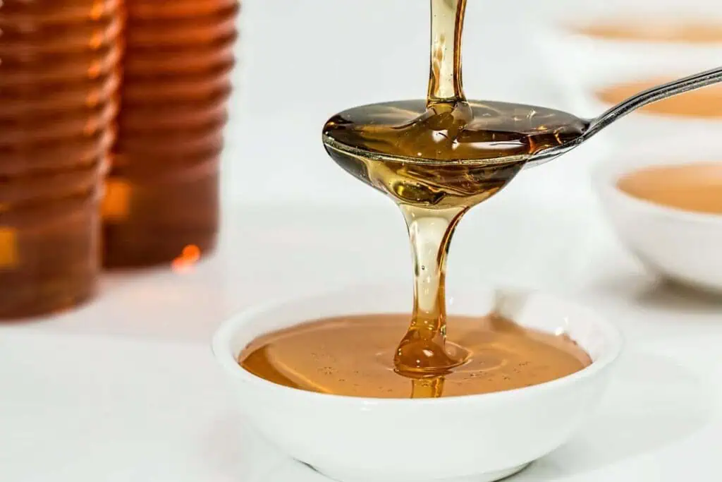Natural, raw honey dripping from a spoon into a bowl.