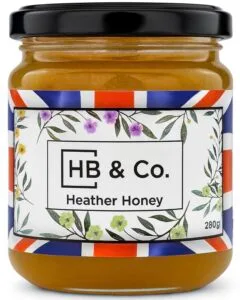 Jar of HoneyBee & Co. Heather Honey 280g with a deep amber colour and floral Union Jack label design.