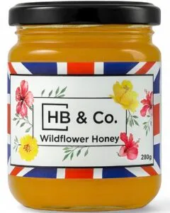 Jar of HoneyBee & Co. Wildflower Honey 280g with a golden amber colour and floral Union Jack label design.