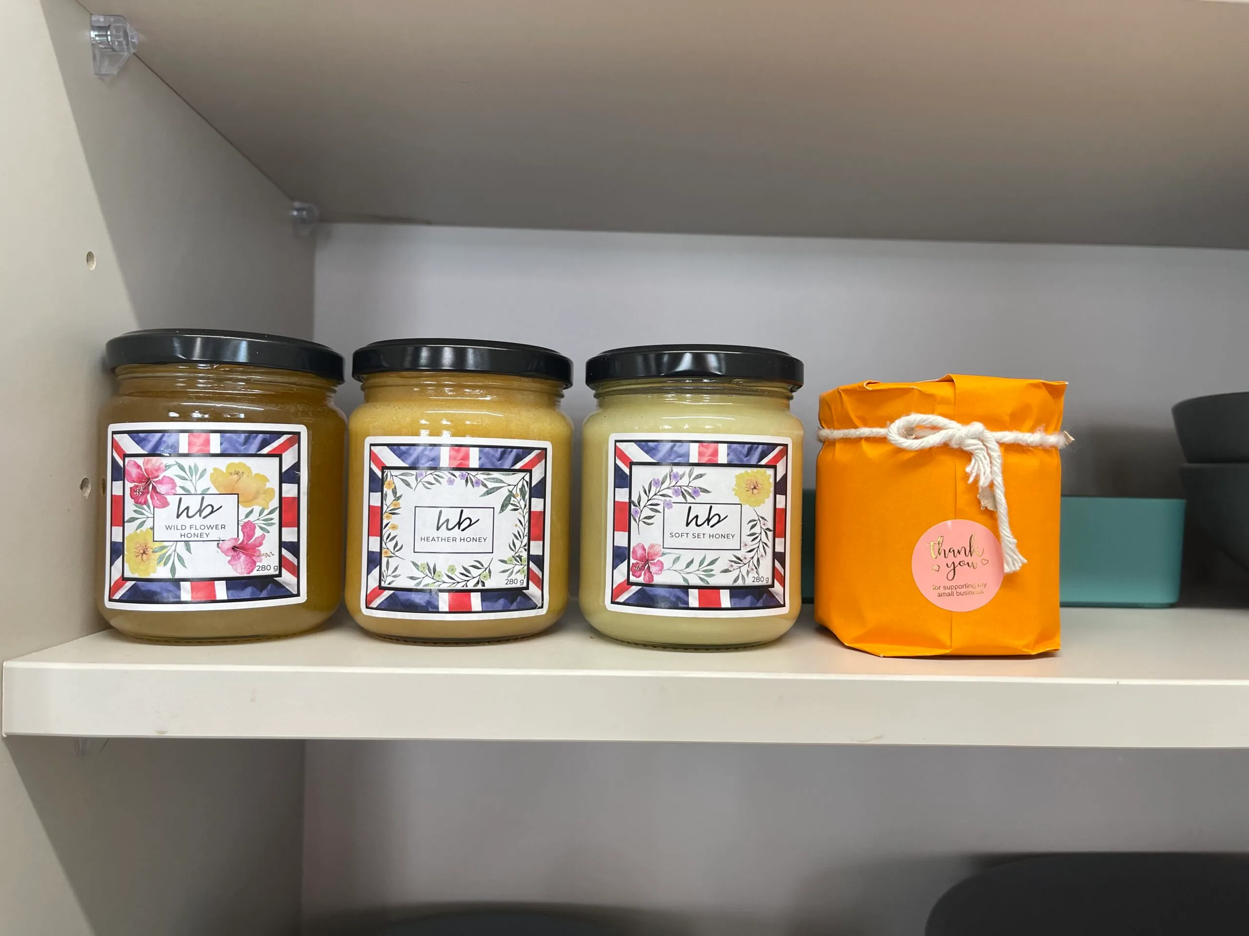 HoneyBee & Co. honey jars on a shelf with a gift-wrapped jar