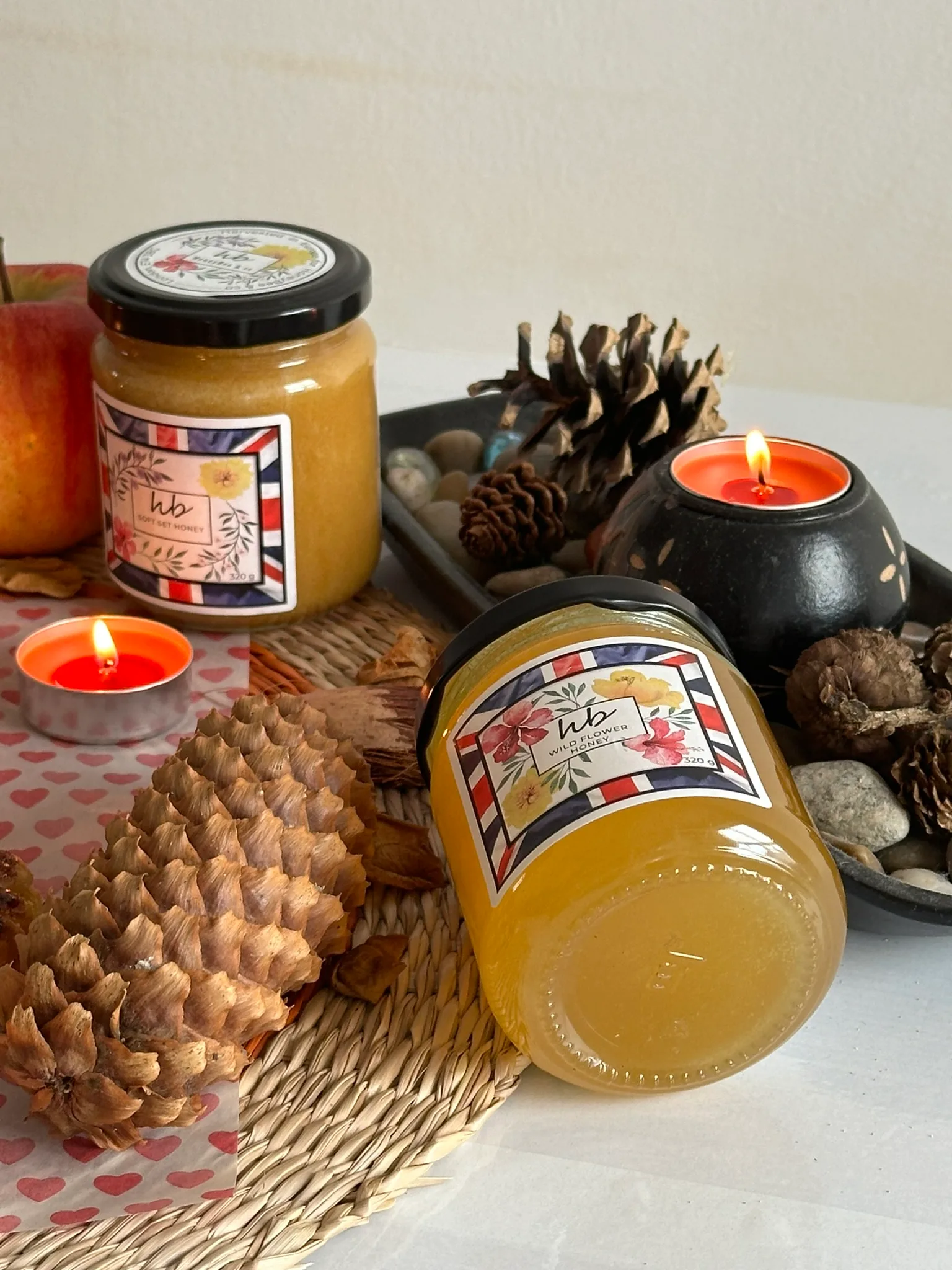 Jars of HoneyBee & Co. Wildflower honey with candles and pinecones
