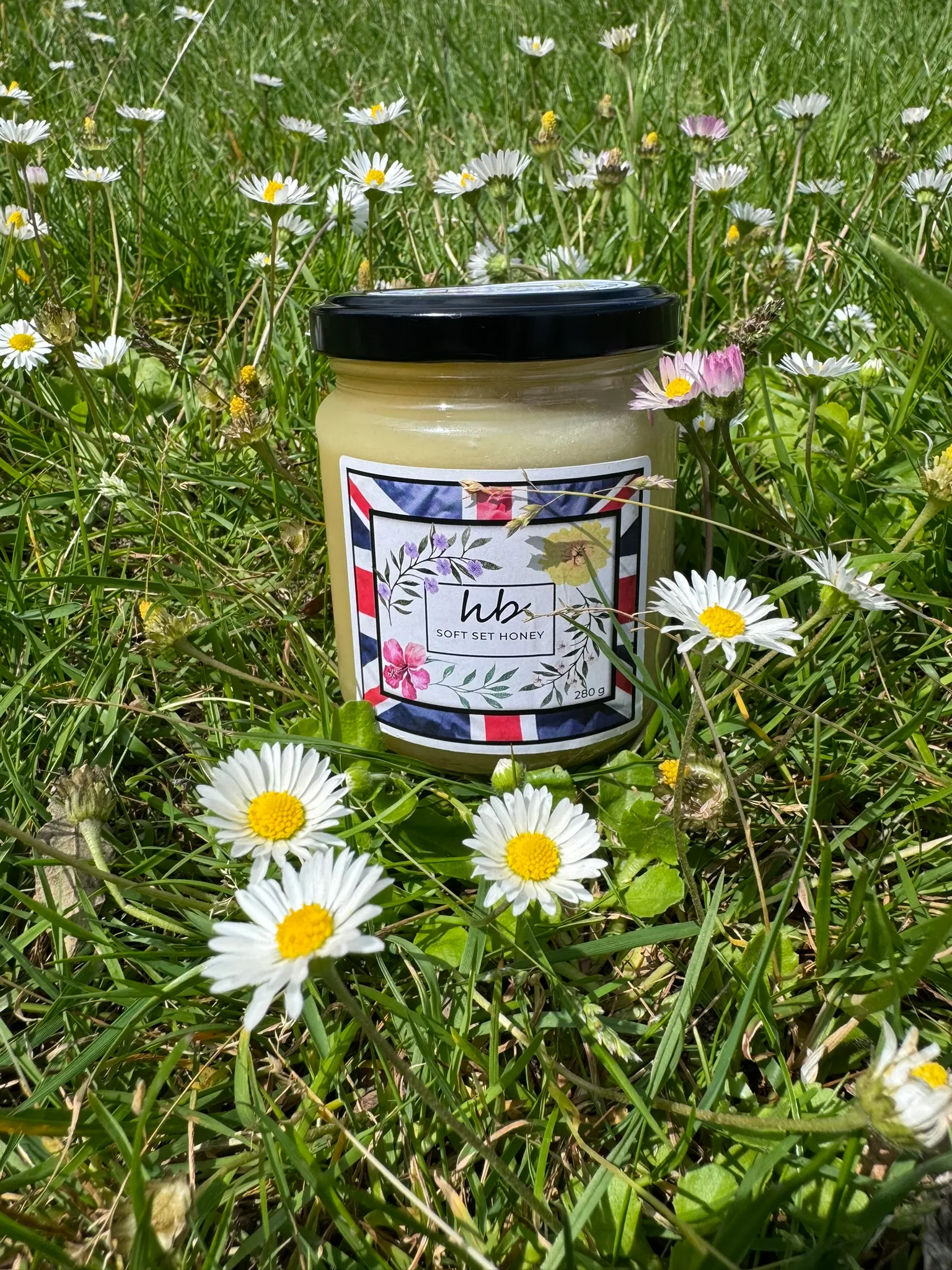 HoneyBee and Co. Soft Set Honey jar in a natural outdoor setting, showing the creamy texture of cold-crystallised British honey