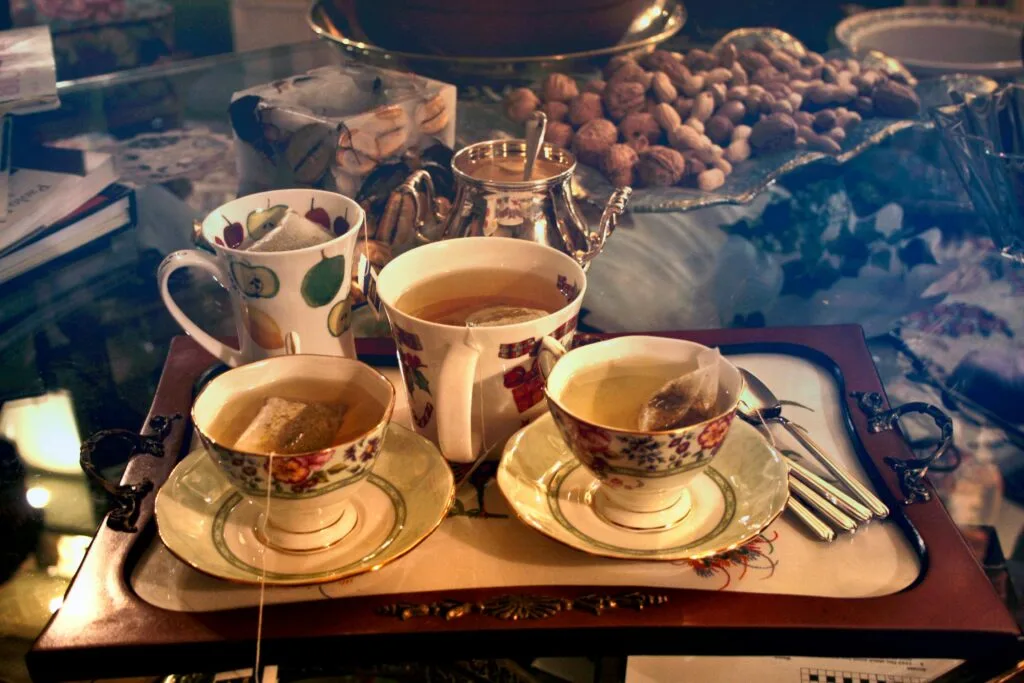 A vintage tea set with cups filled with honey-sweetened tea, surrounded by biscuits and nuts on a decorative tray, creating a warm and comforting atmosphere.

