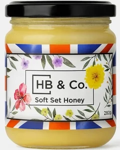 Jar of HoneyBee & Co. Soft Set Honey 280g with a creamy golden texture and floral Union Jack label design.