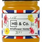 Jar of HoneyBee & Co. Wildflower Honey 280g with a golden amber colour and floral Union Jack label design.