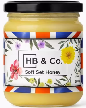 Vasetto di miele HoneyBee & Co. Soft Set da 280 g, dalla consistenza cremosa e dorata, con etichetta floreale Union Jack.