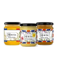 Vasetti di miele assortiti di HoneyBee & Co. con etichette colorate e coperchi neri.